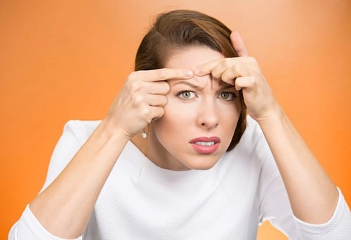 a woman squeezing her pimple